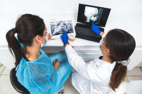 Young dentists discussing over x-ray image and using laptop at clinic