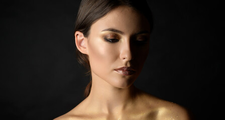 Close-up portrait of young woman with golden makeup.