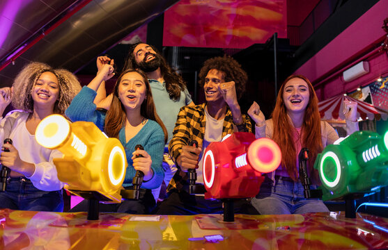 Excited multiracial friends playing in amusement arcade