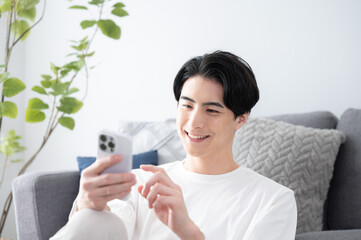 スマホを持って素敵なカメラ目線で笑顔の男性　コピースペースあり...