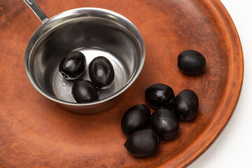 Black olives on a ceramic plate and in a metal bowl.