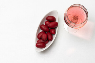 Glass of rose wine and olives in a white plate.