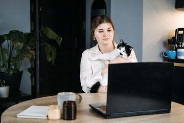 Veterinary Telemedicine Services, Online veterinarian services for virtual pet care. Young woman with cat and using laptop for video call meeting and telemedicine with veterinary from home