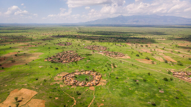 Aerial view taken by drone of "manyattas", typical african villages with mountains in the background on a sunny day, Karamoja, Uganda