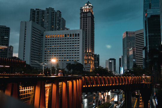 A breath taking view of a ship-shaped pedestrian bridge called "Pinisi" with tall buildings and twilight skies in the background in Karet, Sudirman area.
