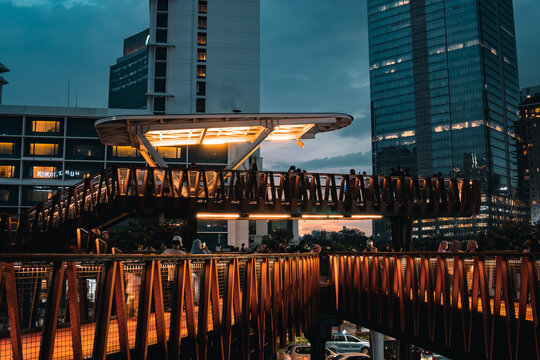 A breath taking view of a ship-shaped pedestrian bridge called "Pinisi" with tall buildings and twilight skies in the background in Karet, Sudirman area.