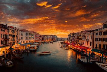 Grand Canal of Venice during sunset with illuminated boats and stores, long exposure