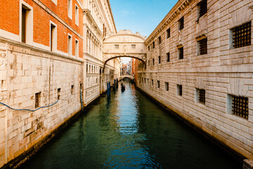 Venice's Bridge of Sighs (Ponte dei Sospiri) with gondolier sailing the canal, blue sky