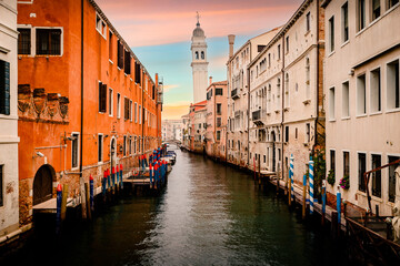 Characteristic canal of Venice at sunset with famous crooked bell tower in the background