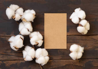 Blank card with cotton flowers top view on dark brown wood, wedding mockup