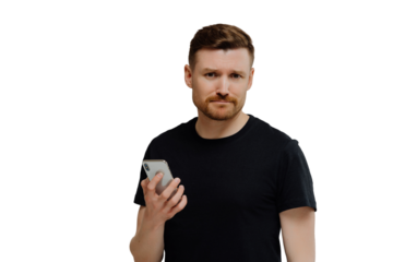 Upset dissatisfied bearded young man holds modern smartphone waits for call frowns face dressed in black casual t shirt isolated over white background being worried about recent terrifying news