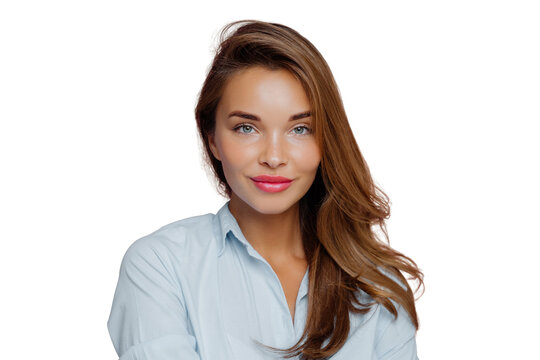 Headshot of lovely European lady has blue eyes, red painted lips, healthy skin, long hair, looks directly at camera, wears shirt, poses over background. Beautiful woman ready for job interview