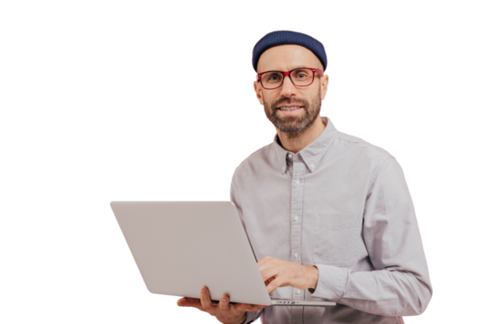 Photo of guy internet user browses website on laptop computer, connected to wireless internet, holds electronic gadget, wears spectacles, formal shirt, isolated over pink background with free space