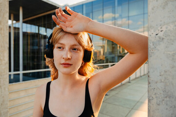 Ginger young woman in headphones listening music during workout