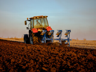Fototapeta premium Farmer in tractor cultivating stubble field for crop planting and cultivation