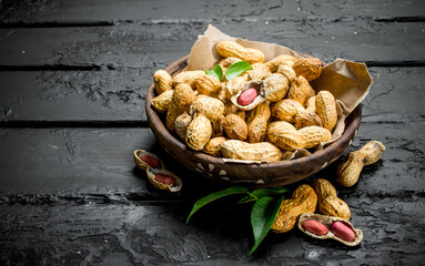 Peanuts in a bowl with leaves .
