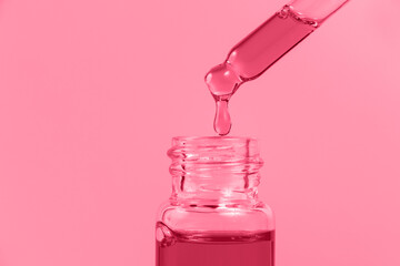 Pipette with a glass bottle on a magenta background.