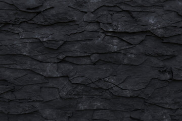 Black grunge rock background. Dark gray fractured stone texture. Mountain cracks close-up backdrop...