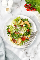 Caesar salad with roasted chicken meat, tomatoes, croutons and parmesan cheese in white plate.