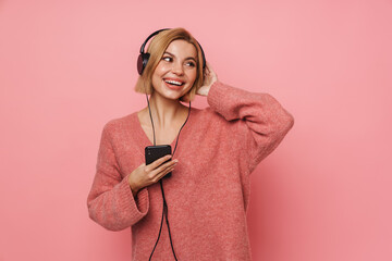 Young blonde woman listening to music with cellphone and headphones