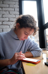 A woman at the table looks at the smartphone screen
