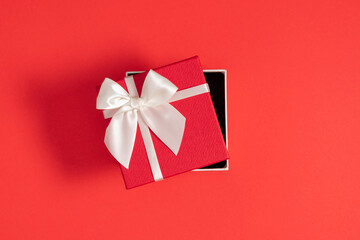 Top view of open red gift box with white bow on red background. Valentine's day, birthday, Christmas, concept, design. Flat lay, copy space