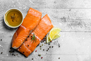 Raw salmon fish steaks with spices and lemon wedges.