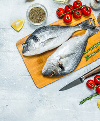 Raw sea fish dorado with spices and tomatoes.