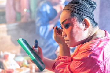 Chinese opera actor cosmetic make up painting face face before perform at back stage of theater