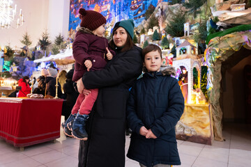 Mother with children visit Christmas nativity crib scene in church.