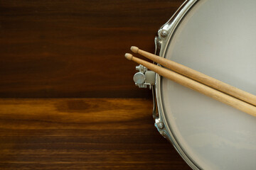 Drum stick snare drum on wooden table background, top view, music concept