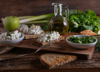 Roasted sourdough bread with cottage cheese salad on wooden table with herbs and olive oil carafe