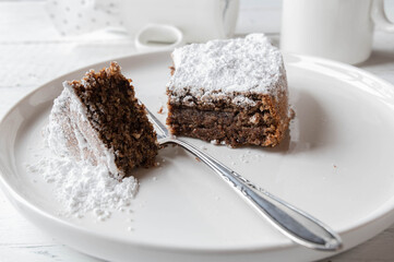 Italian chocolate, almond cake, torta caprese served sliced on a white plate with fork. Closeup and front view