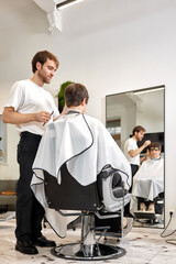 caucasian man getting haircut by professional male hairstylist