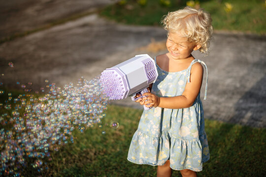 Soap bubble game. Portrait of a girl 4-5 years old outdoors in summer.