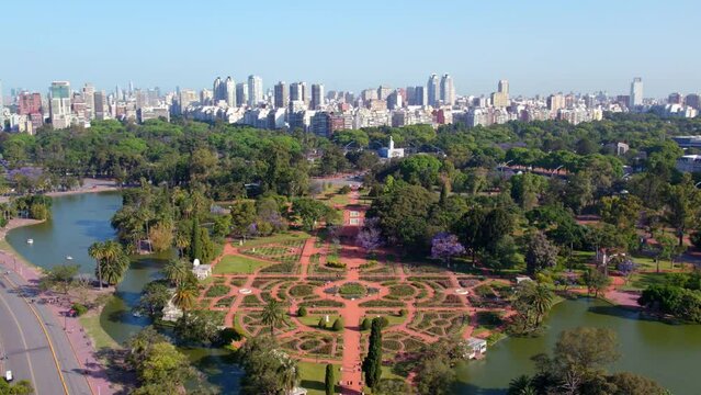 Aerial view dolly in the design of the palermo rose garden with the skyline of the neighborhood in the background, residential buildings of the city of Buenos Aires, Argentina.
