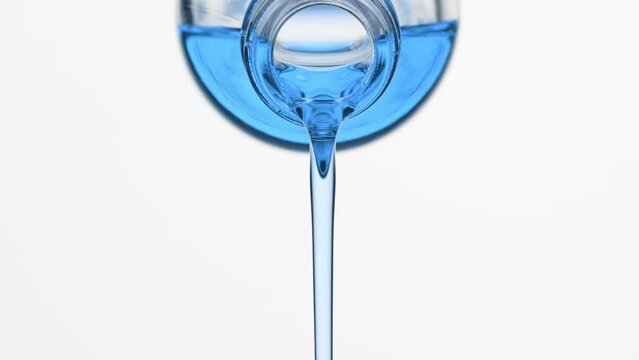 Macro shot of blue tansy oil is being poured from reagent bottle on grey background | Abstract skin nourishing cosmetics ingredients formulating concept