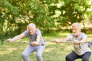 Senioren mit Krücken machen Kniebeuge im Garten