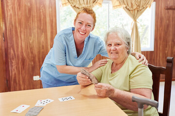 Altenpflegerin und Seniorin beim Skat spielen - obrazy, fototapety, plakaty