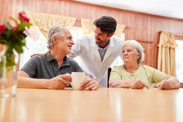 Freundlicher Arzt spricht mit Senioren Paar im Pflegeheim