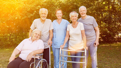 Gruppe Senioren im Garten von Pflegeheim mit Pflegerin