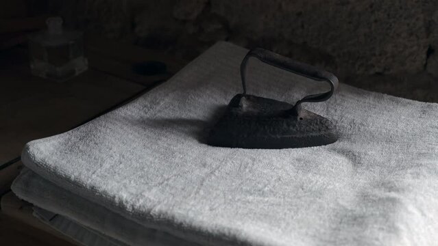 Plancha antigua sobre unas toallas a la que le entra luz de una puerta que se abre