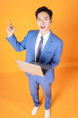 Image of young Asian businessman using laptop on background