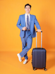 Image of young Asian business man holding suitcase on background