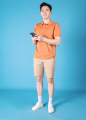 Fototapeta na wymiar Image of young Asian man holding smartphone on blue background