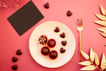 Heart shaped and classic chocolate sweets, golden fork and decorations. Black postcard mock up, elegant wishes concept. Romantic dinner concept. Golden decorations. View from above