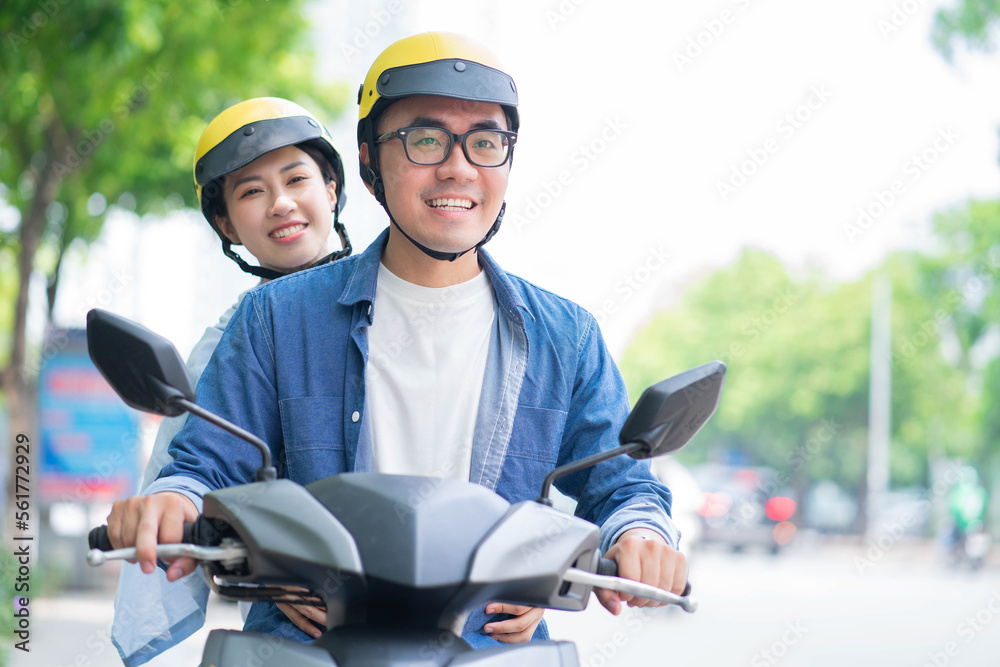 Wall mural Photo of young Asian couple driving motorbike