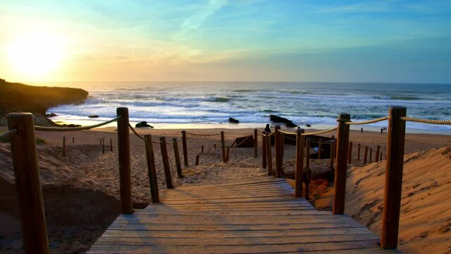 Vivid Sunset over ocean wooden path to beach in Portugal Atlantic Guincho coast, near Sintra Estoril Cascais wide shot