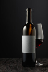 Fototapeta premium Bottle and glass of red wine on a black table.