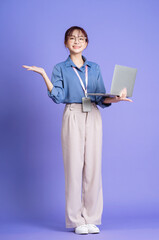Photo of young Asian businesswoman holding laptop on background